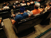 Brazilians strapped to moving chair (3-D cinema showing awful dinosaur movie)